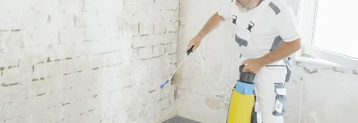 Person trägt Flüssigkeit auf Wand auf